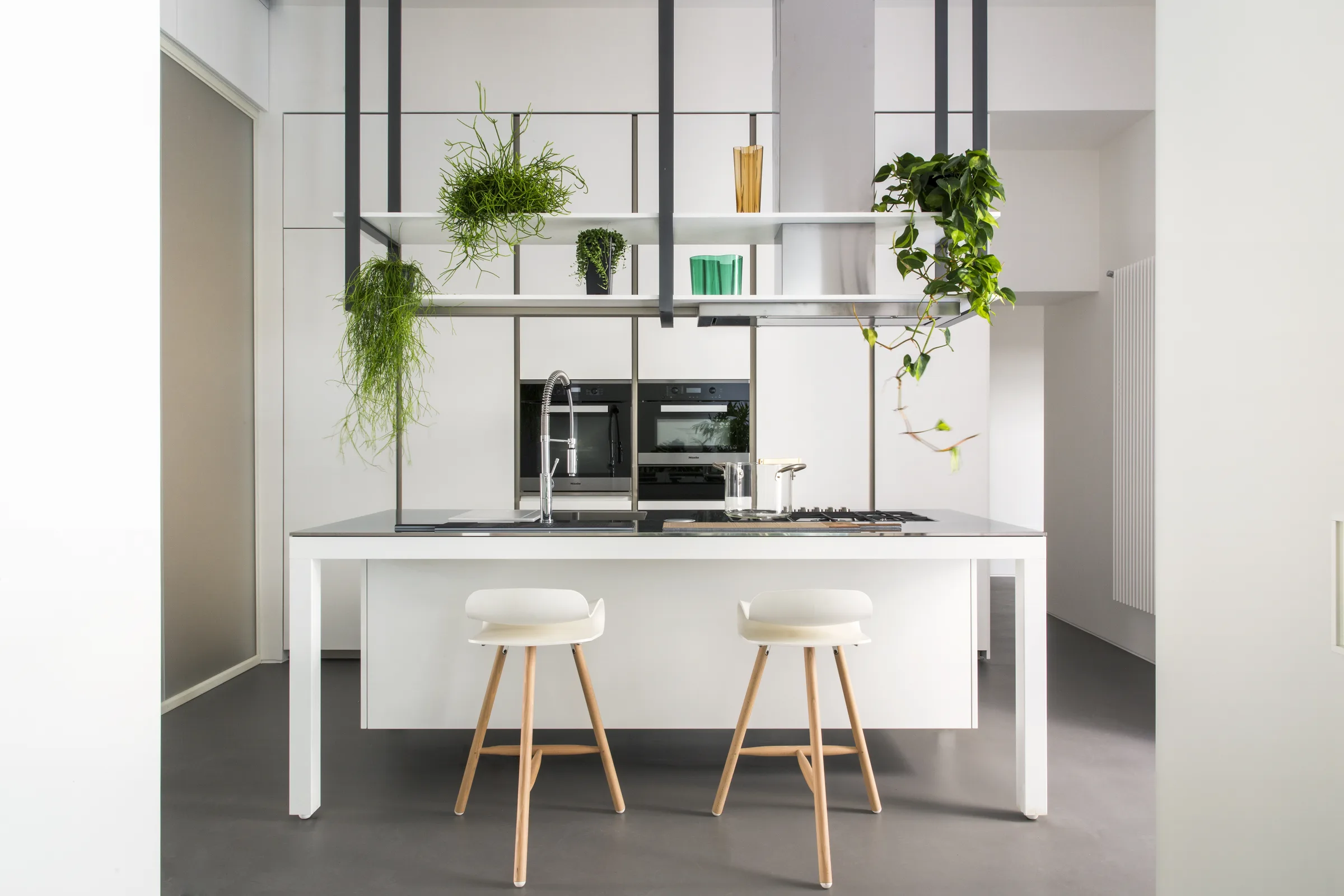 White island with two stools and suspended shelves full of plants