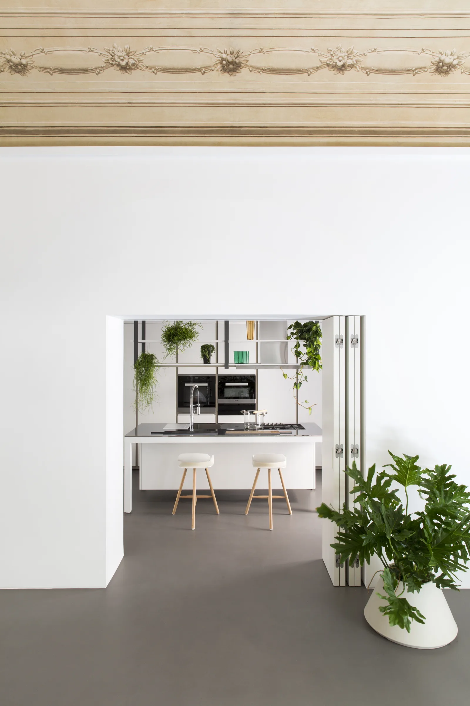 The opening to the kitchen below the painted frieze, in vertical framing