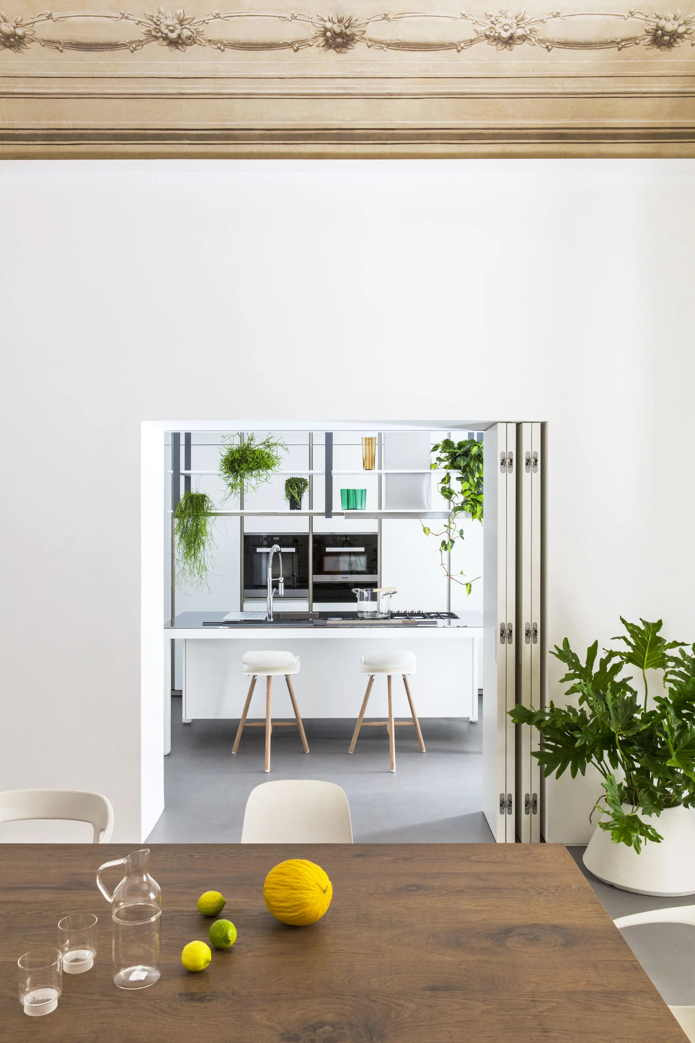 The kitchen seen through the folded doors, with lemons on the table in the foreground