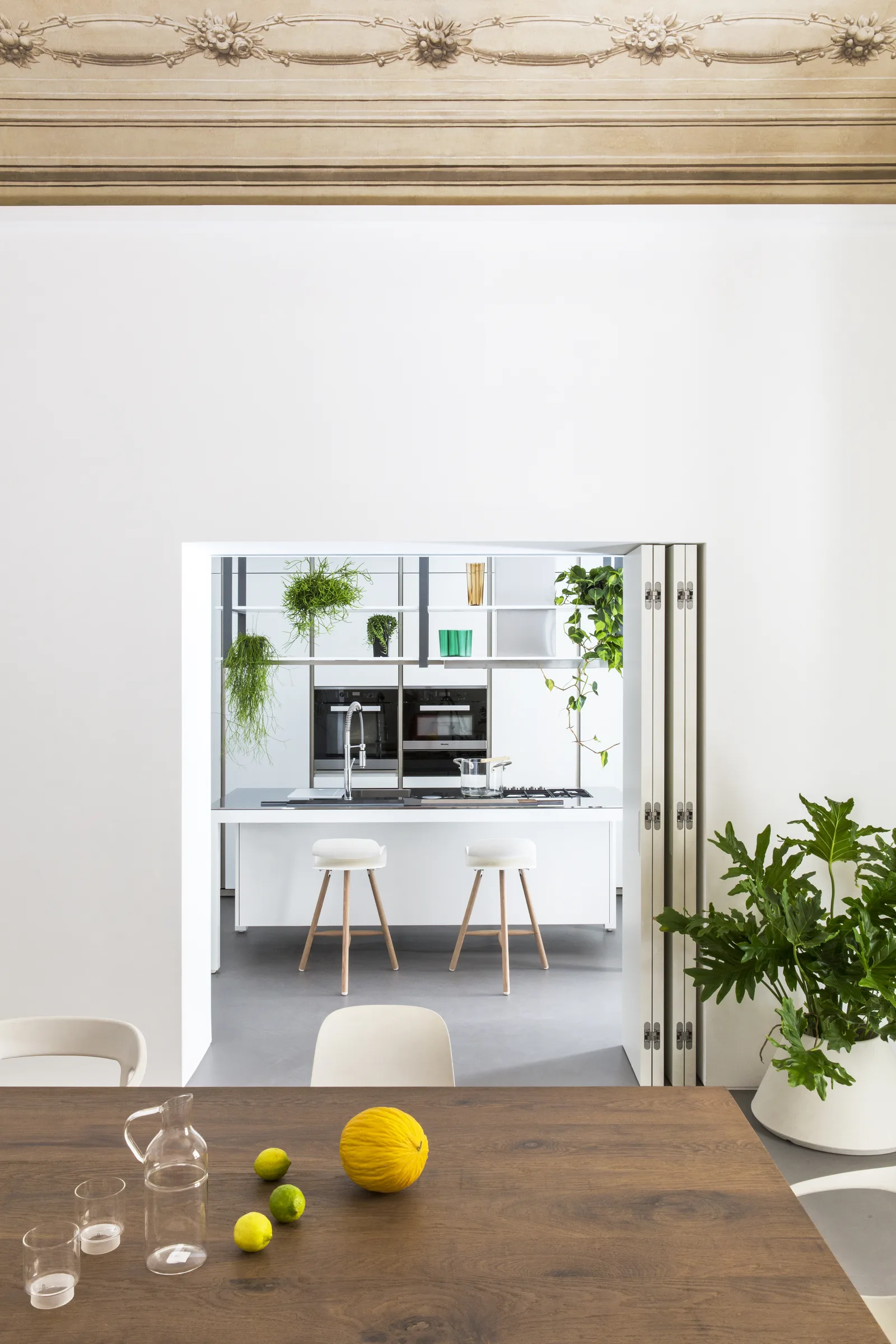 Table with lemons and carafes, and the kitchen framed by the doorway beyond