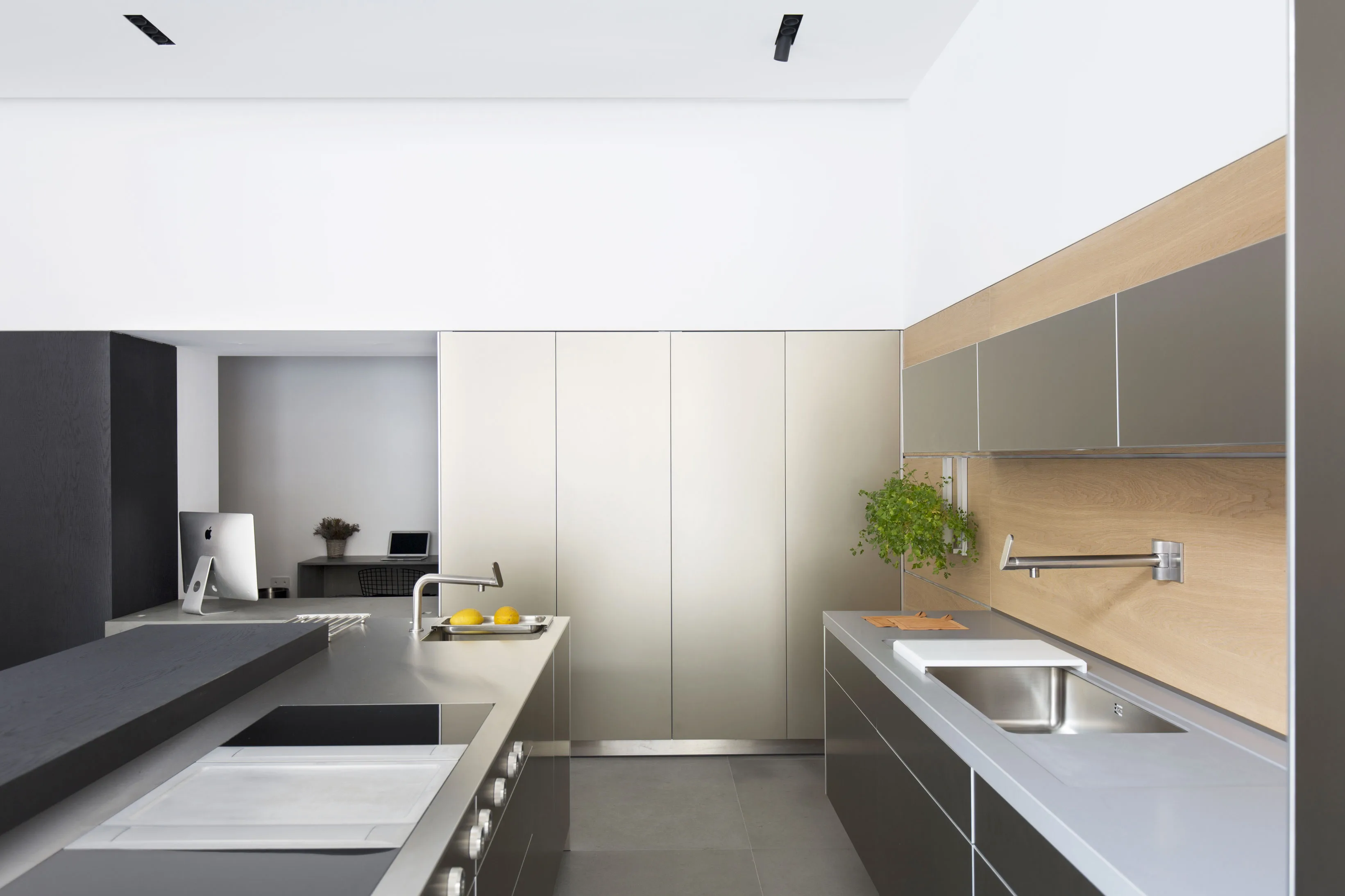 Cucina lineare con ante in acciaio satinato, schienale in legno e piano in acciaio con lavello