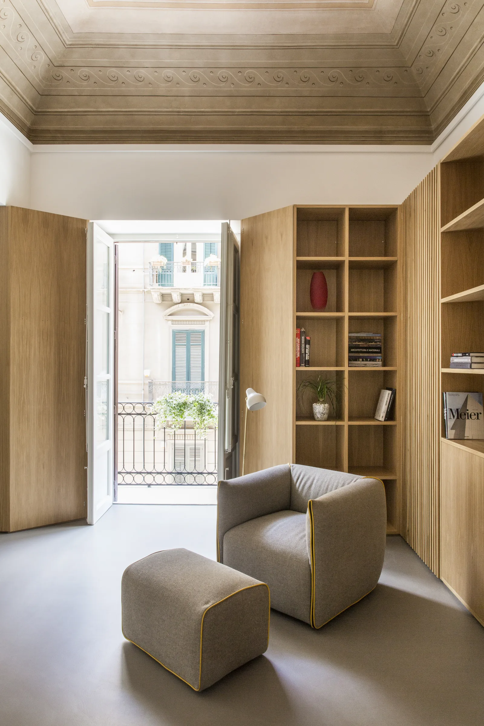 Armchair and oak bookcase beside the window opening onto the balcony