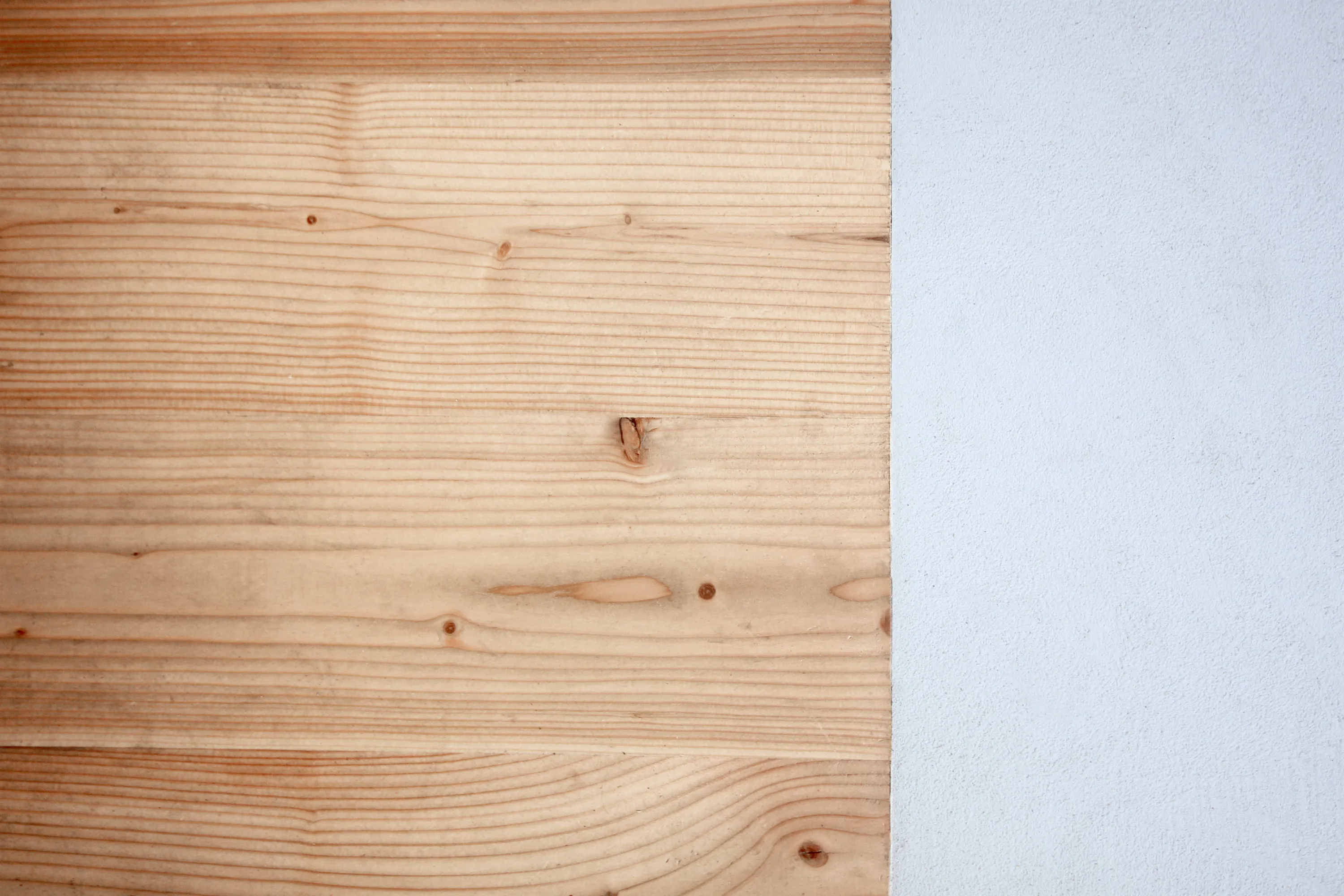 Campione di legno d'abete chiaro accanto a una superficie bianca opaca