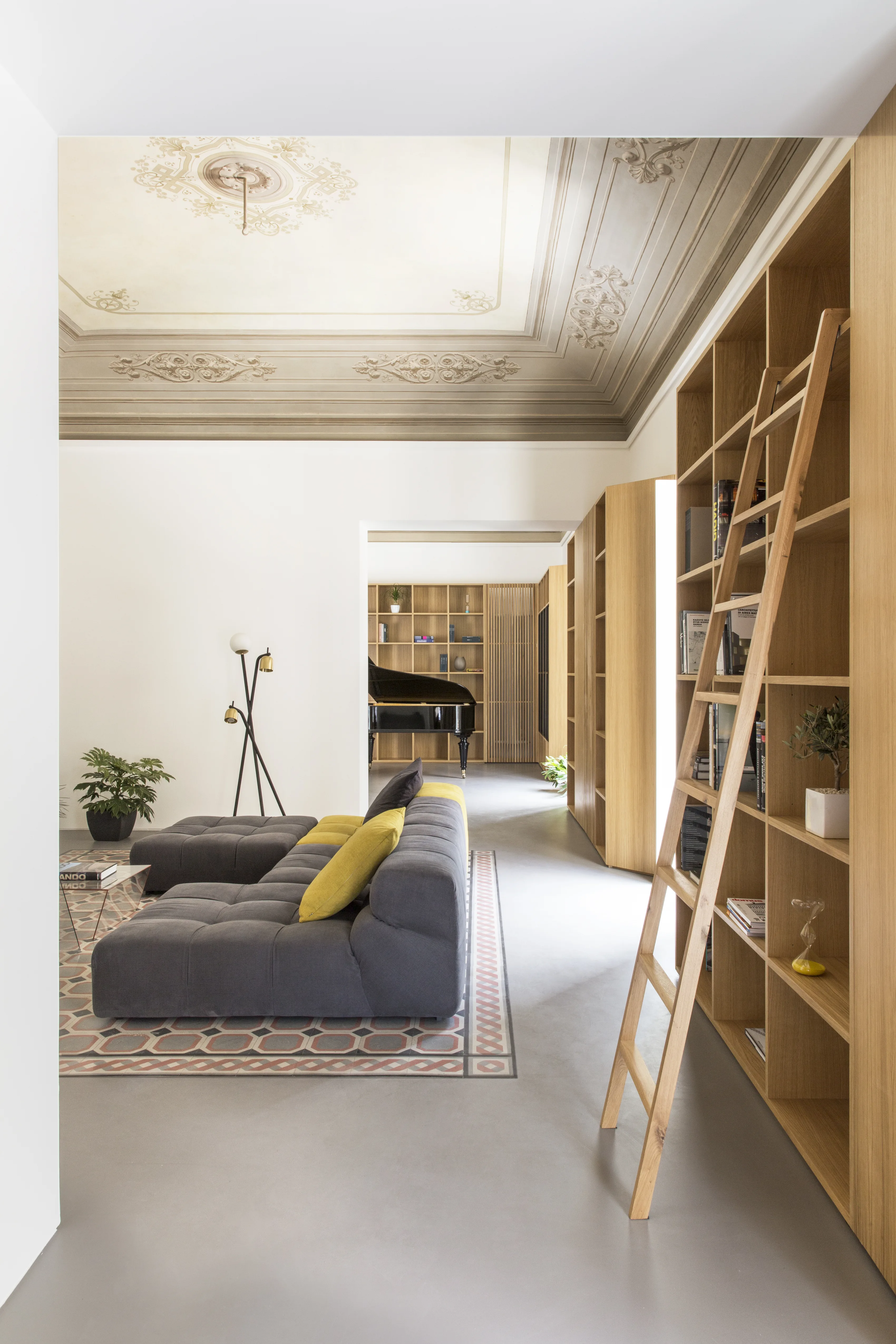 Sitting room with an oak bookcase and sliding ladder, and a long vista of rooms in sequence