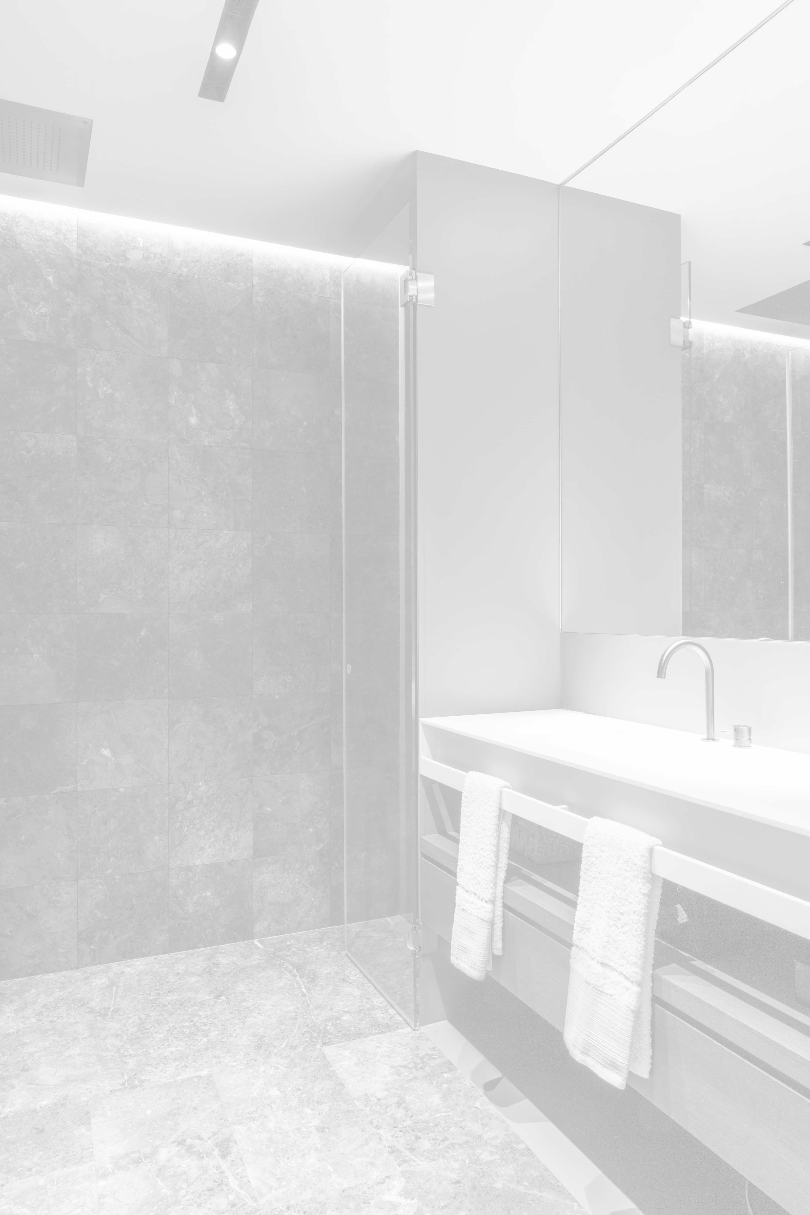 Doccia in pietra con anta in vetro e lavabo con specchio, in versione sfumata a luce lattiginosa