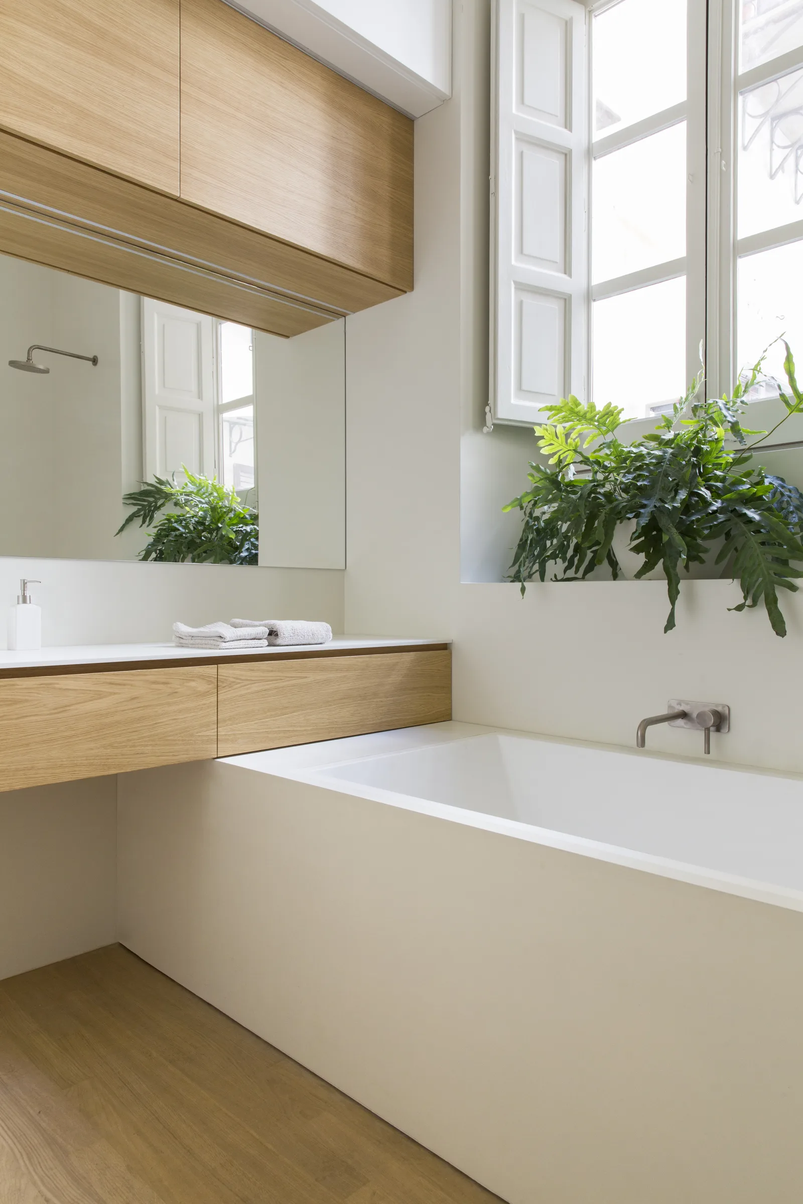 Detail of the bathtub and the vanity top beside the open window