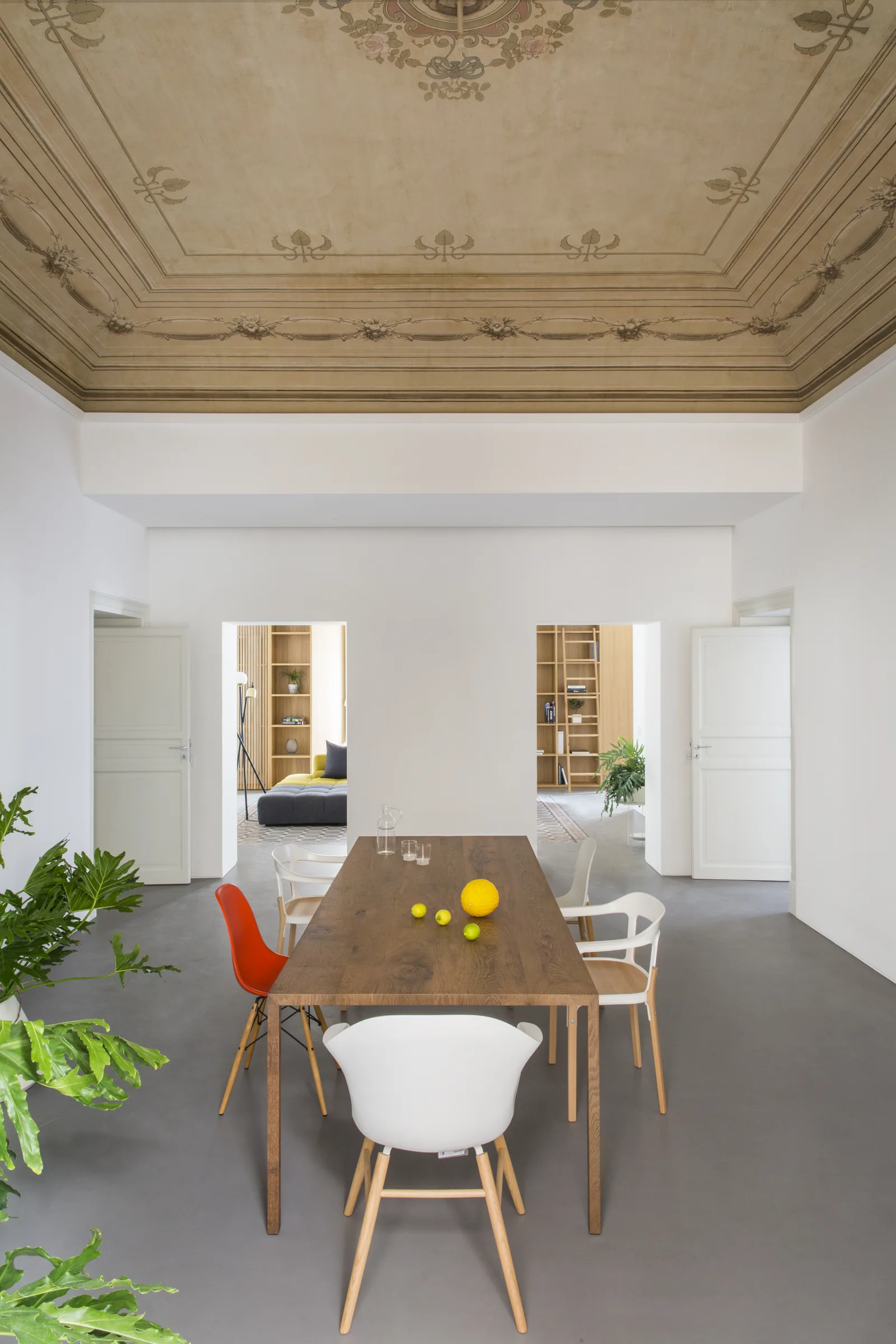 Table with lemons and white and orange chairs, with the rooms in sequence beyond