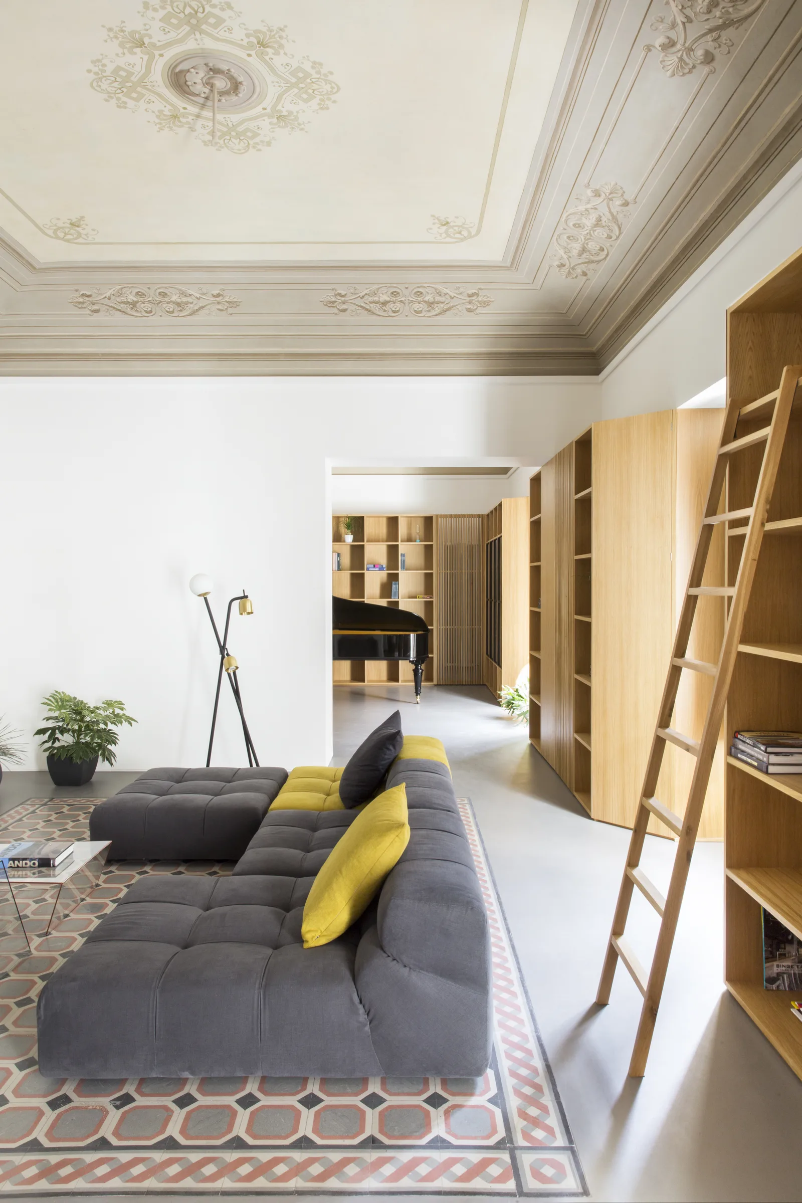 Grey sofa with a yellow cushion, bookcase ladder and coloured tiles on the floor