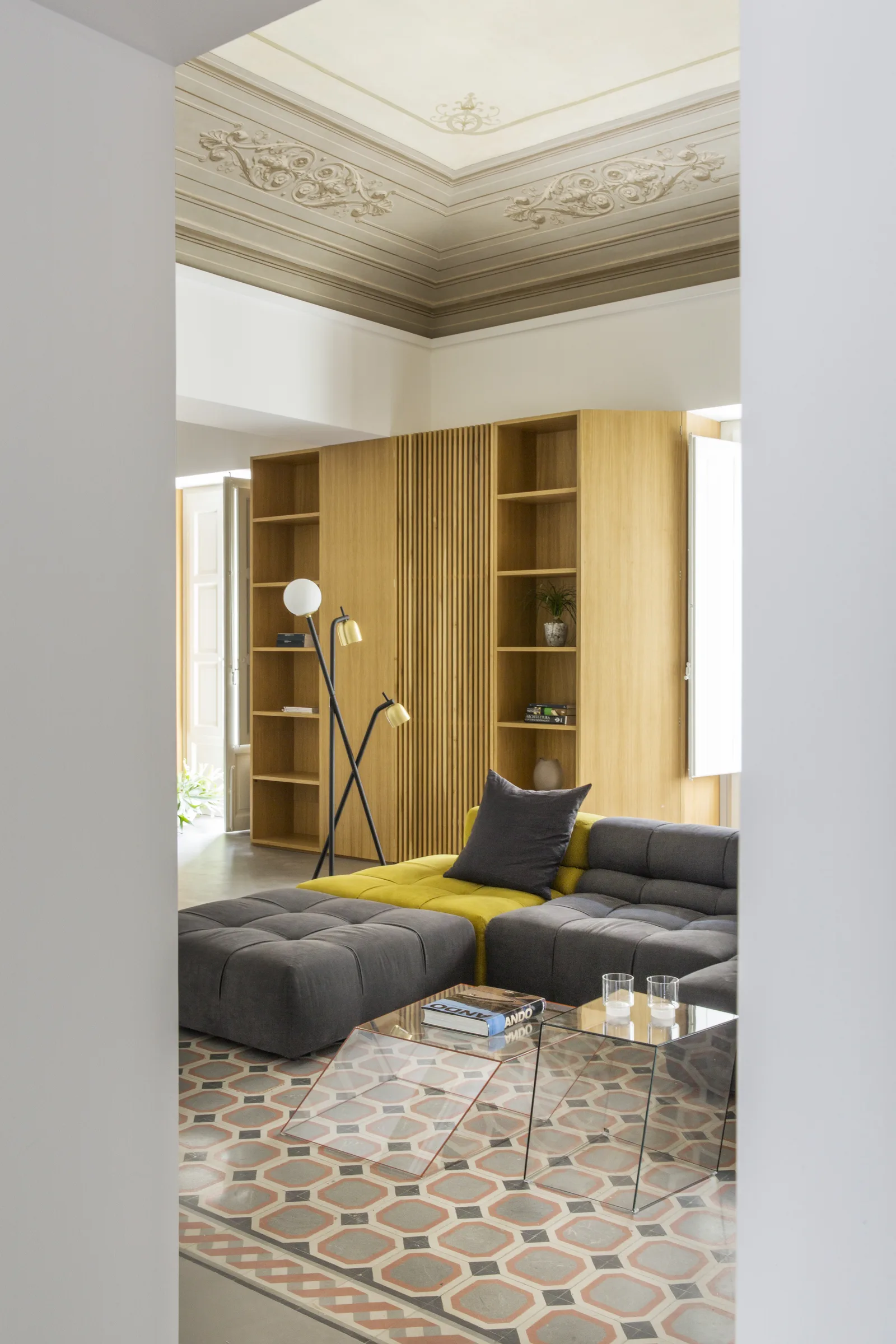 Sofa and glass coffee table on decorated tiles, seen from a side opening