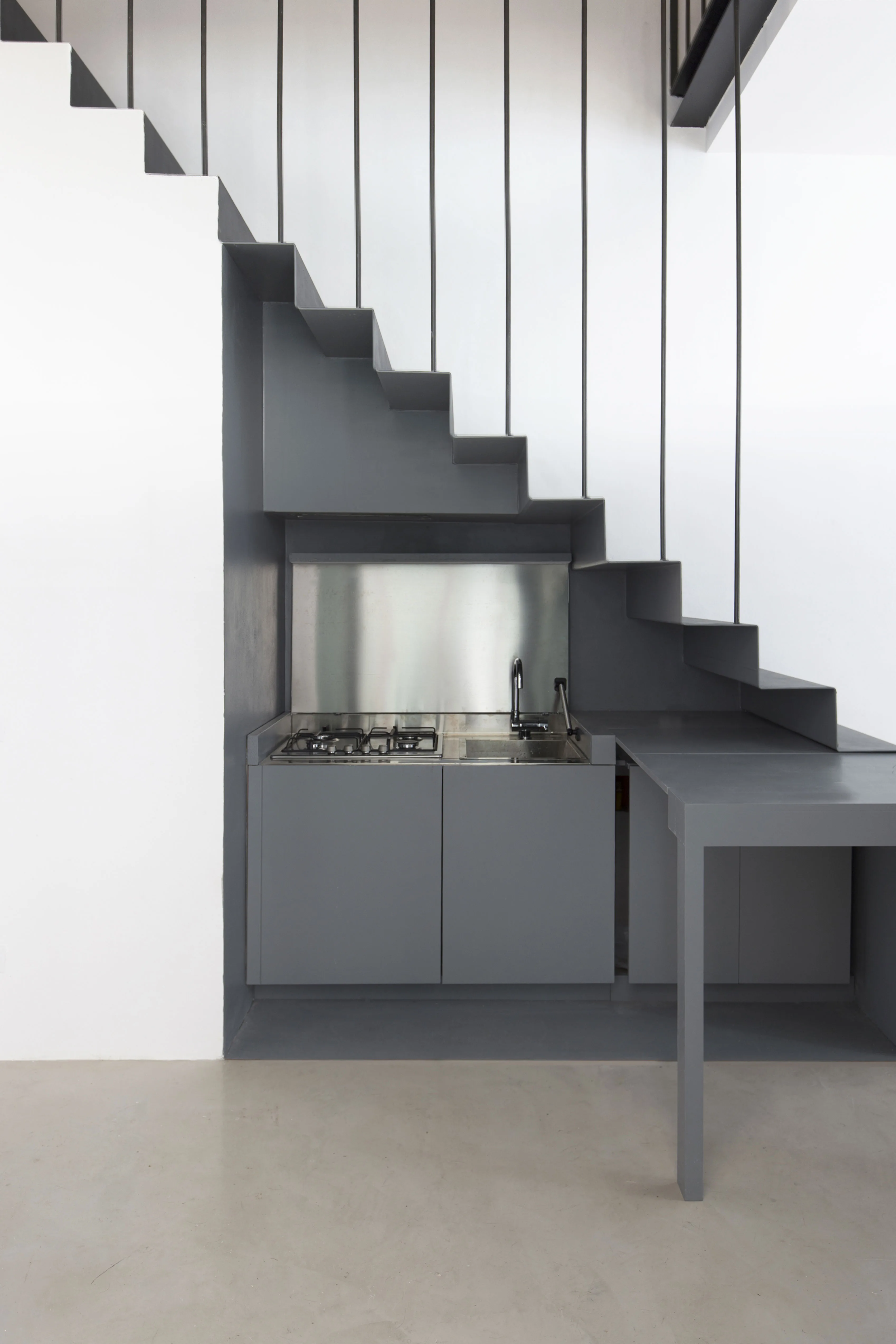 Kitchen under the stair with a grey drop-leaf table opened on the right