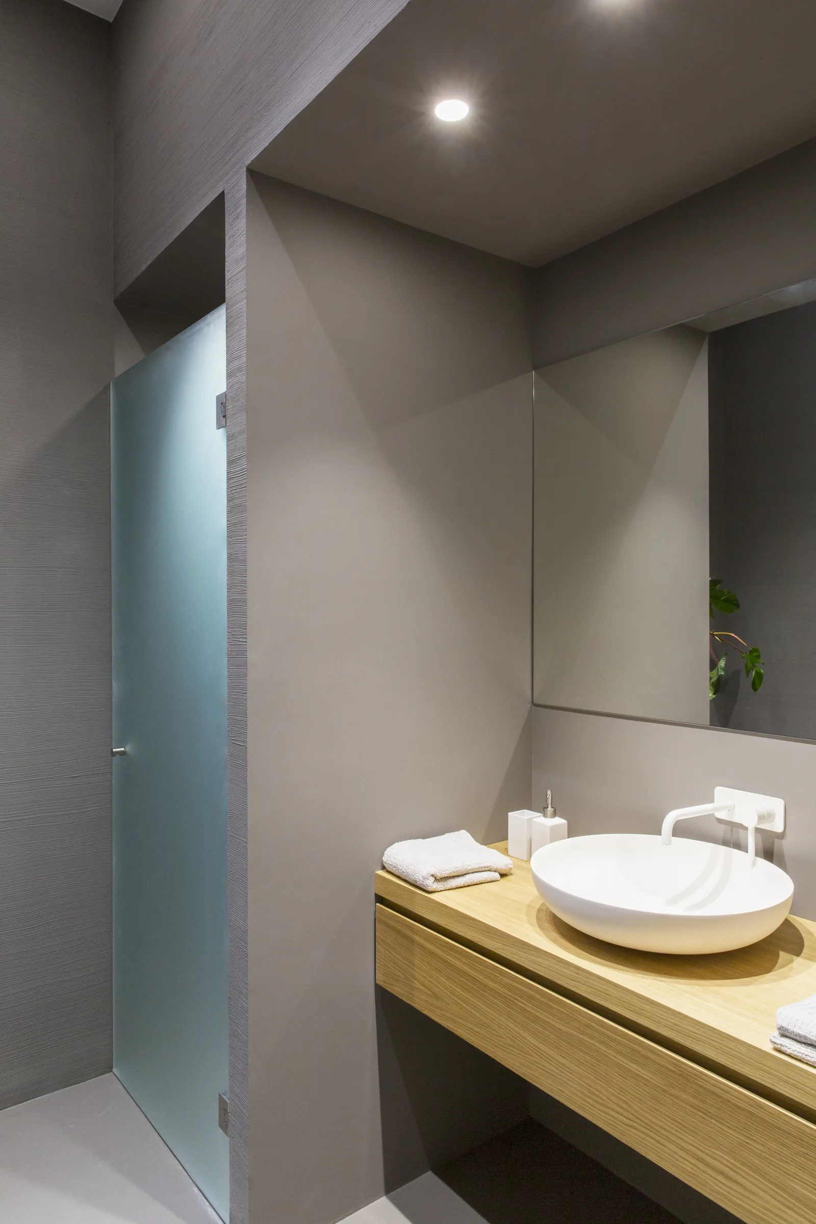 Grey powder room with vessel basin on a wooden unit and mirror
